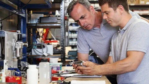 Engineer Helping Male Apprentice In Factory Stock-Footage 93376765