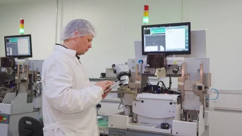 Engineer at high-tech factory compares machine analytical data with Stock Footage 318166225