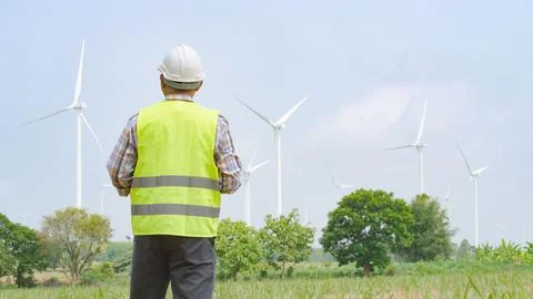 Engineer holding blueprint while surveying wind turbines at renewable energ.. Stock Photos