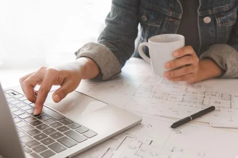 Engineer holding coffee cup while using a computer laptop to  planning projec Stock Photos