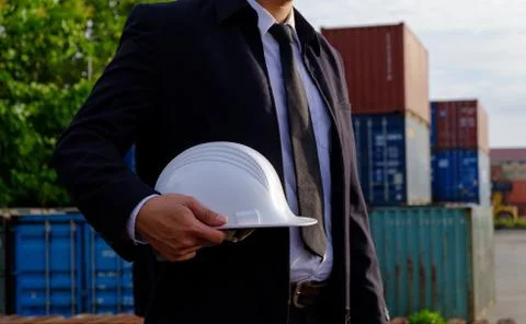 The engineer is holding a helmet on containers background. Stock Photos