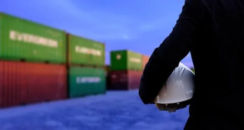 The engineer is holding a helmet on containers background. Stock Photos