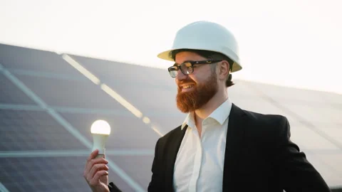 Engineer holding light bulb in front of solar panel farm Video stock 314410042