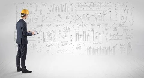 Engineer holding a plan and standing with graphs, charts and reports on the 스톡 사진
