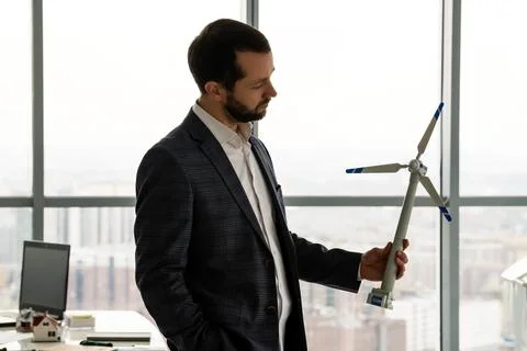 Engineer holding wind turbine model overlooking city Stock Photos
