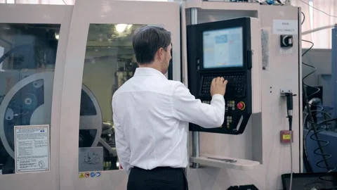 An engineer at an industrial plant. A worker controls the operation of a CNC Stock Footage 171774942