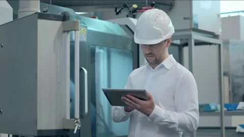 An engineer at an industrial plant. A worker controls the operation of a CNC Stock Footage 171774948