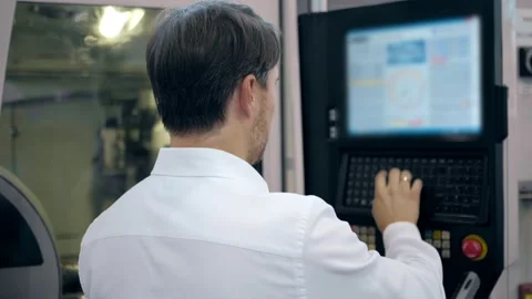An engineer at an industrial plant. A worker controls the operation of a CNC Stock Footage 171774959