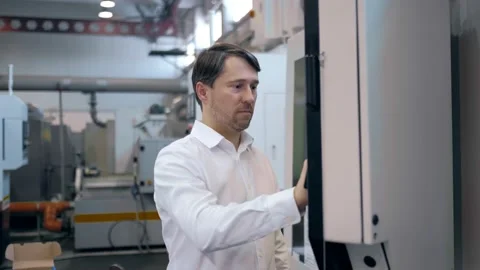 An engineer at an industrial plant. A worker controls the operation of a CNC Stock Footage 171774966