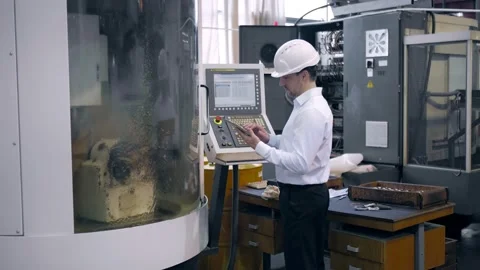 An engineer at an industrial plant. A worker controls the operation of a CNC Stock Footage 171774978
