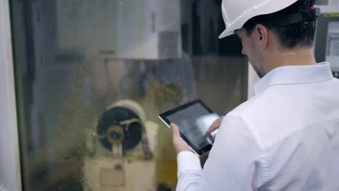 An engineer at an industrial plant. A worker controls the operation of a CNC Stock Footage 171774981