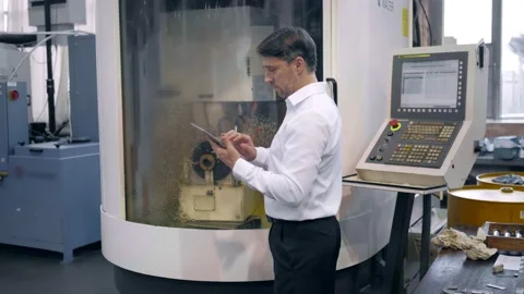 An engineer at an industrial plant. A worker controls the operation of a CNC Stock Footage 171775004