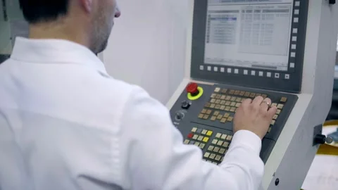 An engineer at an industrial plant. A worker controls the operation of a CNC Stock Footage 171775022