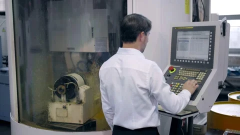 An engineer at an industrial plant. A worker controls the operation of a CNC Stock Footage 171775023