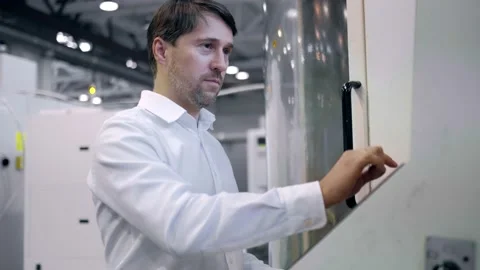 An engineer at an industrial plant. A worker controls the operation of a CNC Stock Footage 171775039