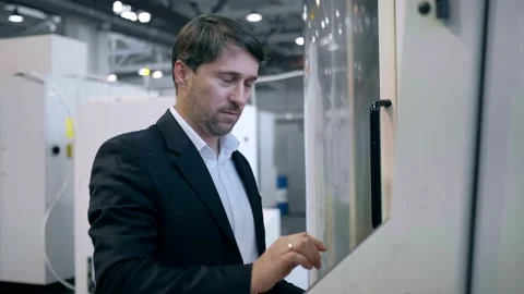 An engineer at an industrial plant. A worker controls the operation of a CNC Stock Footage 171775041