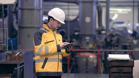 An engineer at an industrial plant. A worker controls the operation of a CNC Stock Footage 171775481