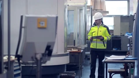 An engineer at an industrial plant. A worker controls the operation of a CNC Stock Footage 171775483