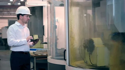 An engineer at an industrial plant. A worker controls the operation of a CNC Stock Footage 172014642