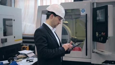 An engineer at an industrial plant. A worker controls the operation of a CNC Stock Footage 172014658