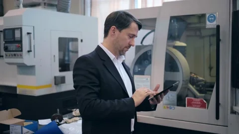 An engineer at an industrial plant. A worker controls the operation of a CNC Stock Footage 172014692
