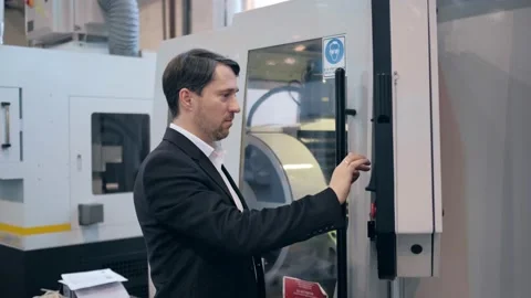 An engineer at an industrial plant. A worker controls the operation of a CNC Stock Footage 172014731