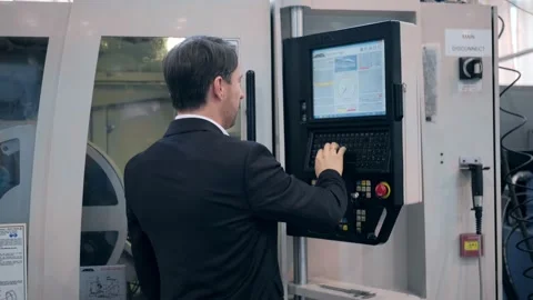 An engineer at an industrial plant. A worker controls the operation of a CNC Stock Footage 172014750