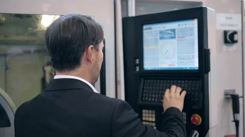 An engineer at an industrial plant. A worker controls the operation of a CNC Stock Footage 172014771