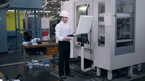 An engineer at an industrial plant. A worker controls the operation of a CNC Stock Footage 172014812