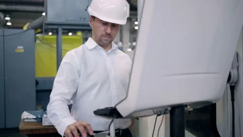 An engineer at an industrial plant. A worker controls the operation of a CNC Stock Footage 172014813