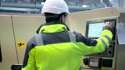 An engineer at an industrial plant. A worker controls the operation of a CNC Stock Footage 172016815