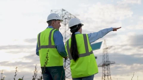 Engineer inspect power transmission lines inputting data on tablet at sunset Stock Footage 265024686