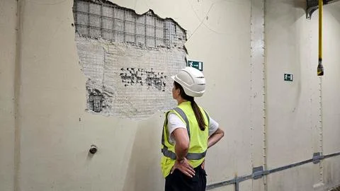 Engineer inspecting cracked wall structure at industrial site Stock Photos