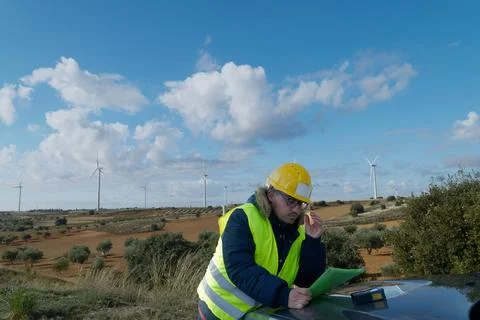 Engineer inspecting documents at wind farm for renewable energy generation Stock Photos