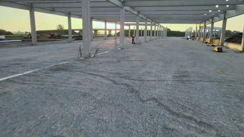 Engineer inspecting modern warehouse under construction from drone perspective Stock Footage 339386914