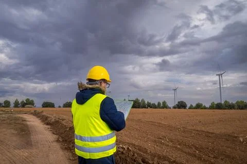 Engineer inspecting plans for wind turbine park development Stock Photos