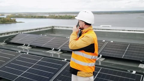 Engineer inspecting rooftop solar panels with walkie-talkie communication. Video stock 330873751