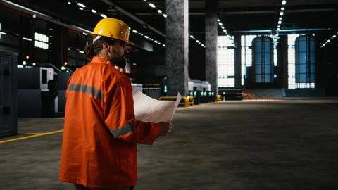 Engineer inspecting technical plans and sketches in heavy industry workshop Stock Photos