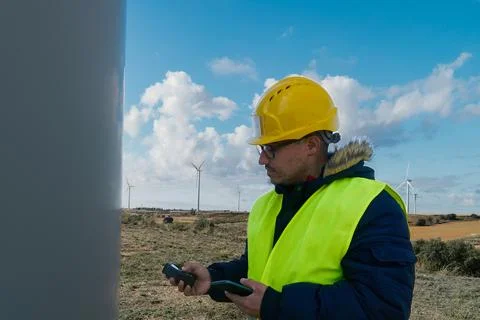 Engineer inspecting wind turbine in operation with digital device Stock Photos