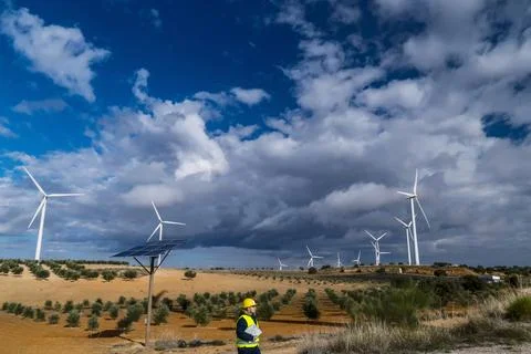 Engineer inspecting wind turbines and solar panel in sustainable energy farm Stock Photos
