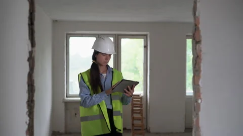 Engineer inspector at a construction site using a tablet calculating Stock Footage 210111584