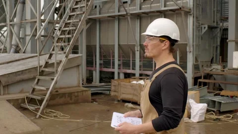An engineer inspects the construction of grain storage silos. Stock Footage 271629291