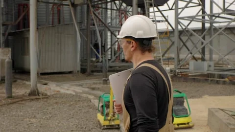 An engineer inspects the construction of grain storage silos. Stock Footage 271629293