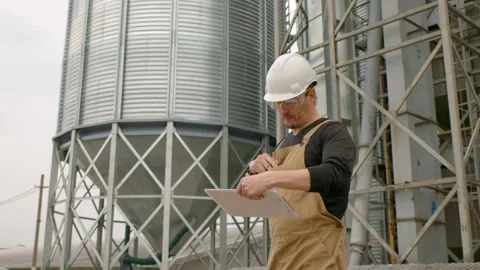 An engineer inspects the construction of grain storage silos. Stock Footage 271629320