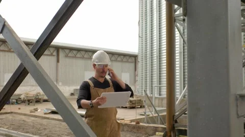 An engineer inspects the construction of grain storage silos. Stock Footage 271629328