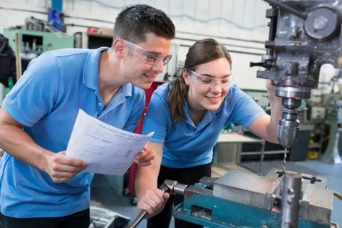 Engineer Instructing Female Apprentice On Use Of Drill Stock Photos