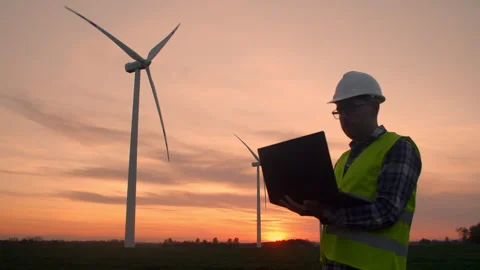 Engineer with a laptop controls the operation of windmills on a field Stock Footage 255409370
