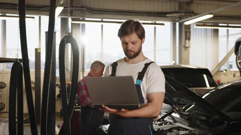 Engineer with laptop makes computer diagnostics of the car engine in auto Stock Footage 243357098