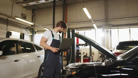 Engineer with laptop makes computer diagnostics of the car engine in auto Stock Footage 243359792