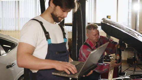Engineer with laptop makes computer diagnostics of the car engine in auto Stock Footage 243360402
